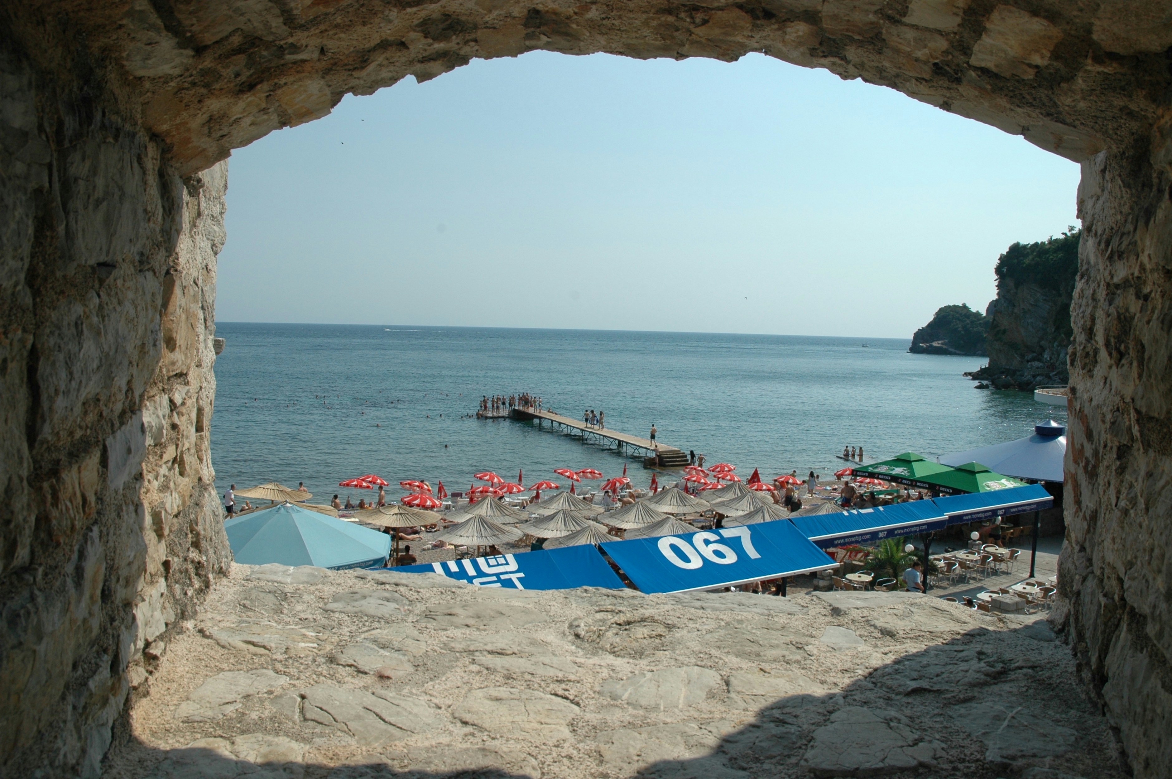 a view of a beach from a window in a stone wall