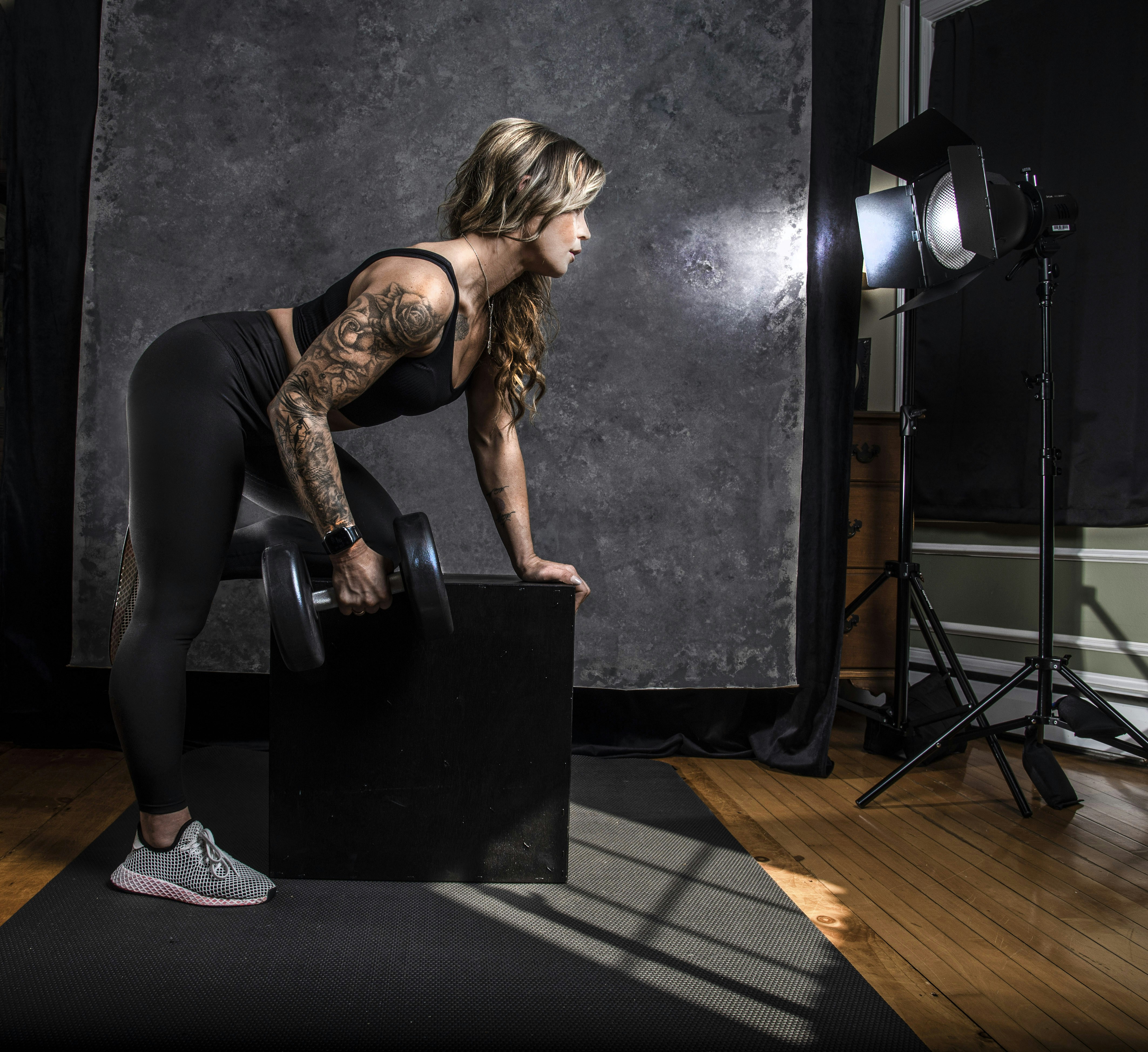 a woman in a black top and leggings holding a black box