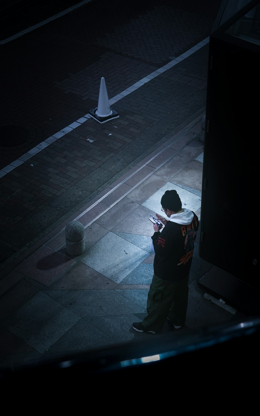 a man standing on a street corner looking at his cell phone