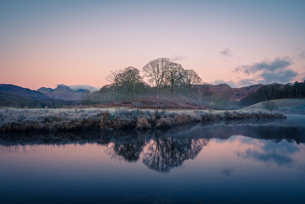 a body of water with trees and mountains in the background