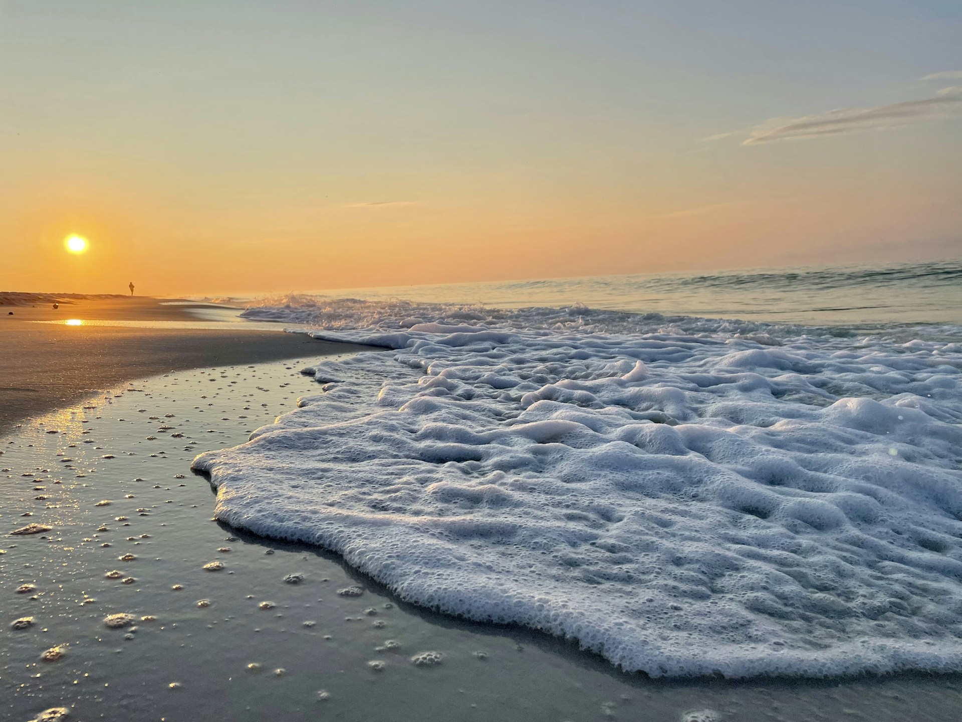 the sun is setting over the ocean with waves coming in