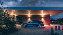 A sturdy carport with clean aluminum lines protecting a family’s vehicles under a bright blue sky.