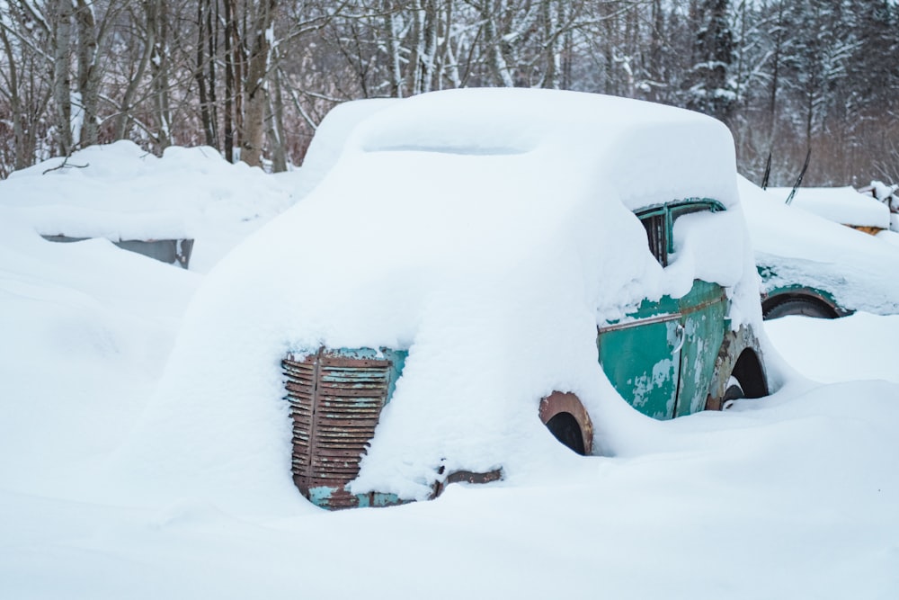 um carro velho coberto de neve em uma área arborizada