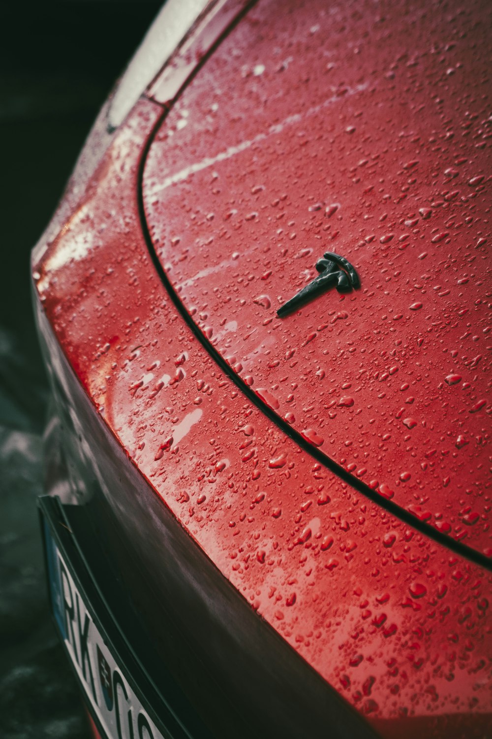 a close up of a red car with water droplets on it