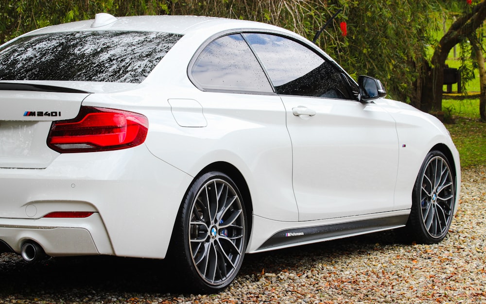 a white bmw car parked on a gravel road
