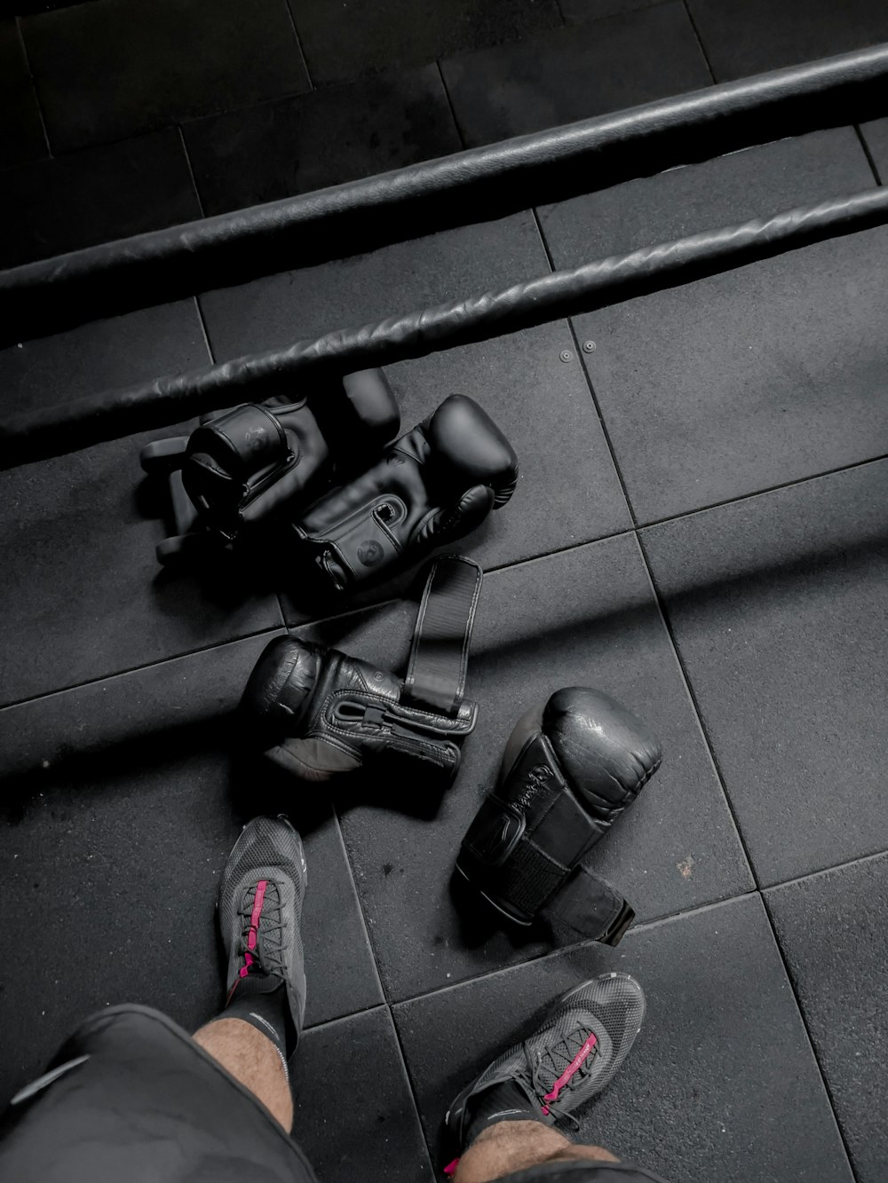 uma pessoa em pé em um piso de azulejos ao lado de um par de sapatos pretos