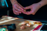 Close-up of a baker's hands shaping cookie dough on a wooden board in a warm kitchen.