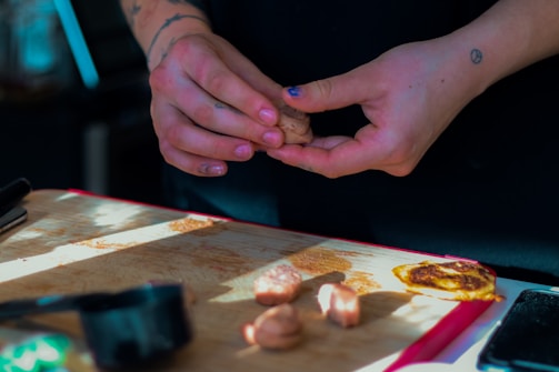 Hands shaping gluten-free bread dough on a rustic wooden board.