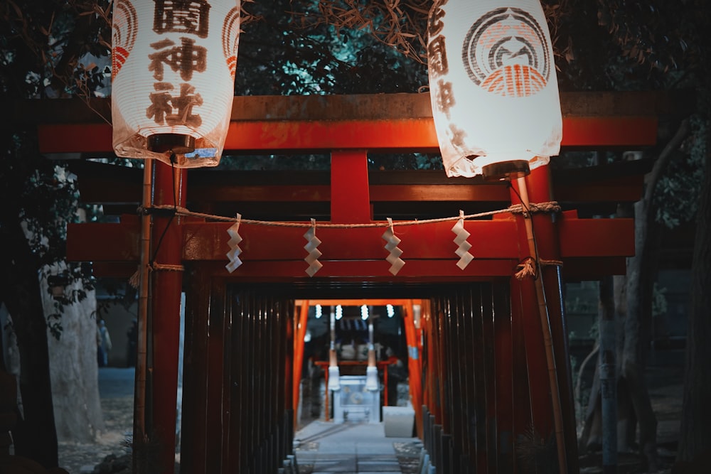 a red gate with two lanterns hanging over it