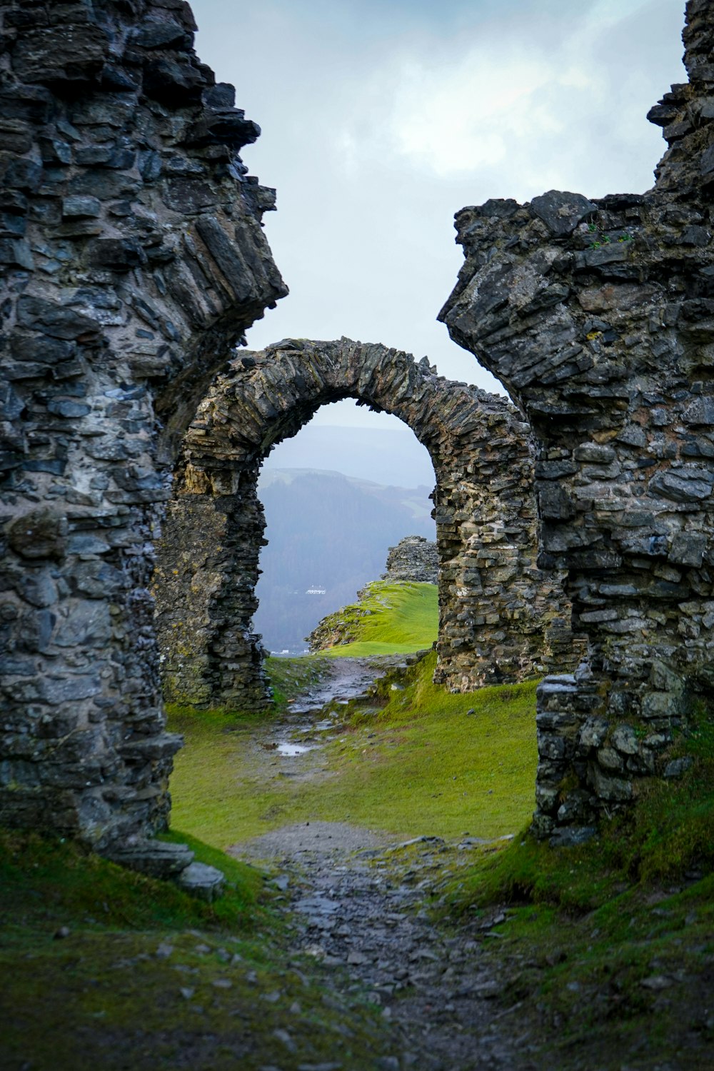 a stone archway leading to a grassy area