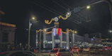 A lively city street at night illuminated with festive lights and joyful visitors.
