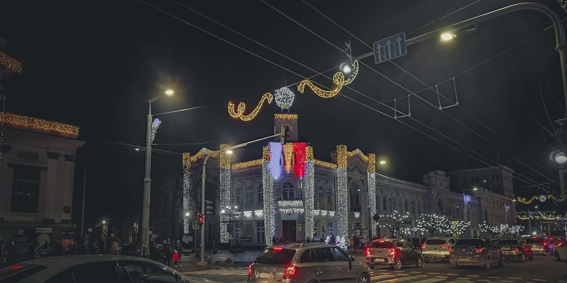 A lively city street at night illuminated with festive lights and joyful visitors.