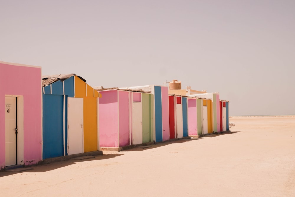 a row of colorful beach huts sitting on top of a sandy beach