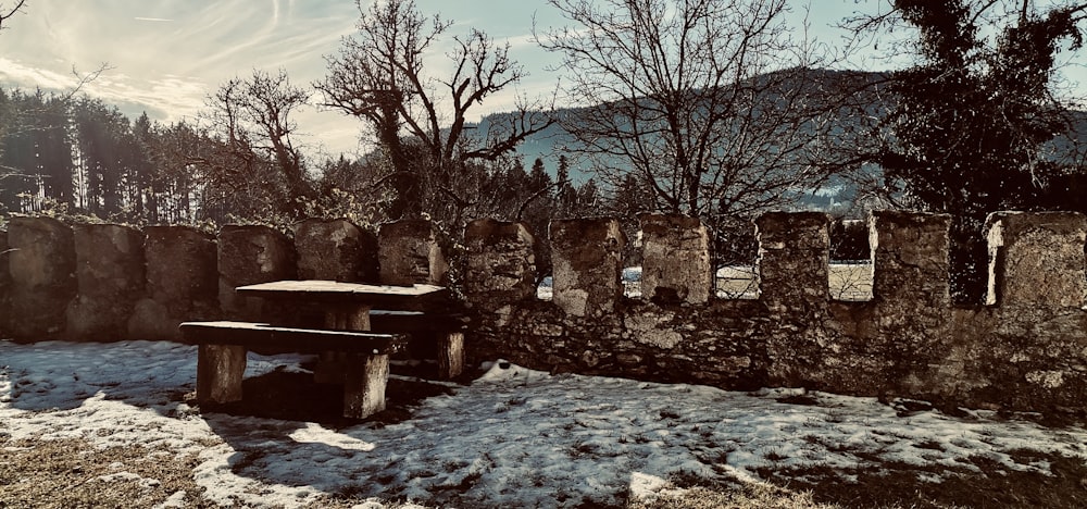 a stone wall with a wooden bench in the snow