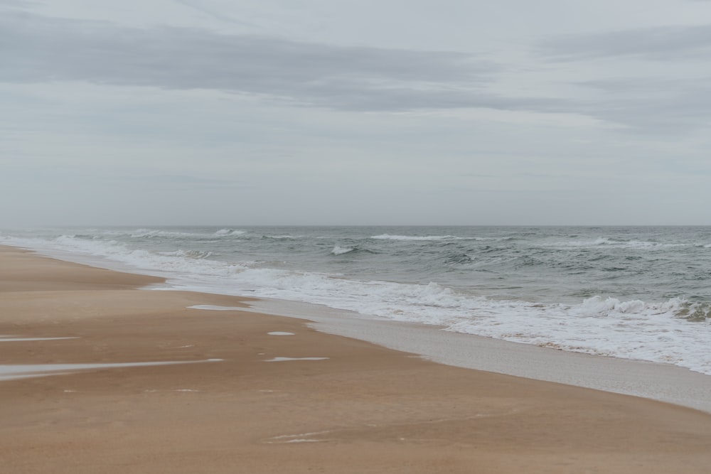 a sandy beach with waves coming in to shore