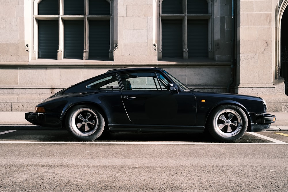 a black porsche parked in front of a building