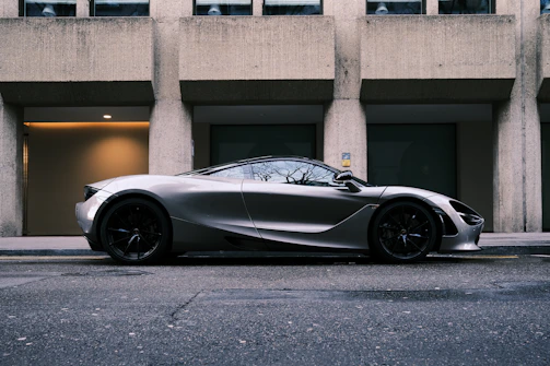 A sleek silver car parked in front of a modern building on a sunny day.