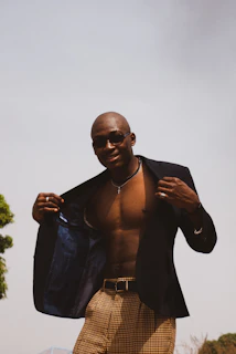 A smiling customer wearing a fitted jacket and relaxed pants, enjoying a sunny day in a park setting.
