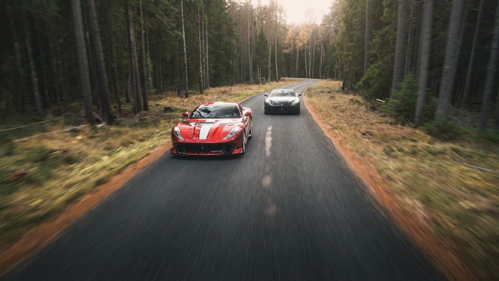 two cars driving down a road in the woods