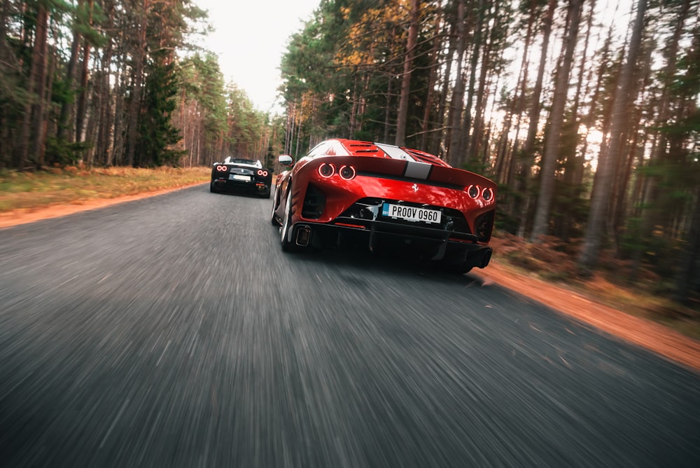 two red sports cars driving down the road