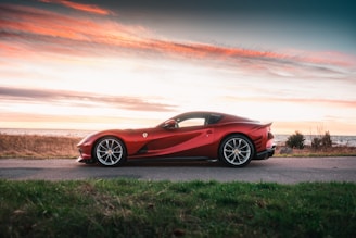 A sleek red Ferrari parked against a sunset backdrop.