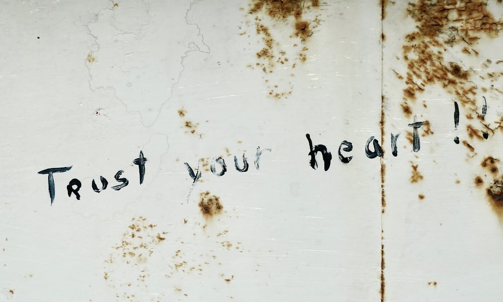 a rusted metal surface with writing that says trust your heart