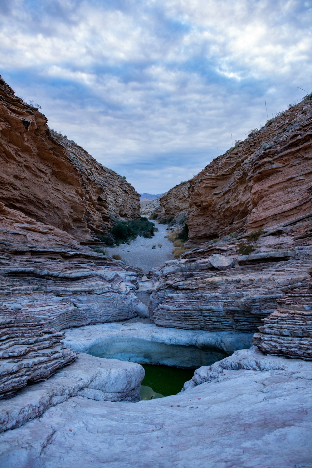 a small pool of water in the middle of a canyon