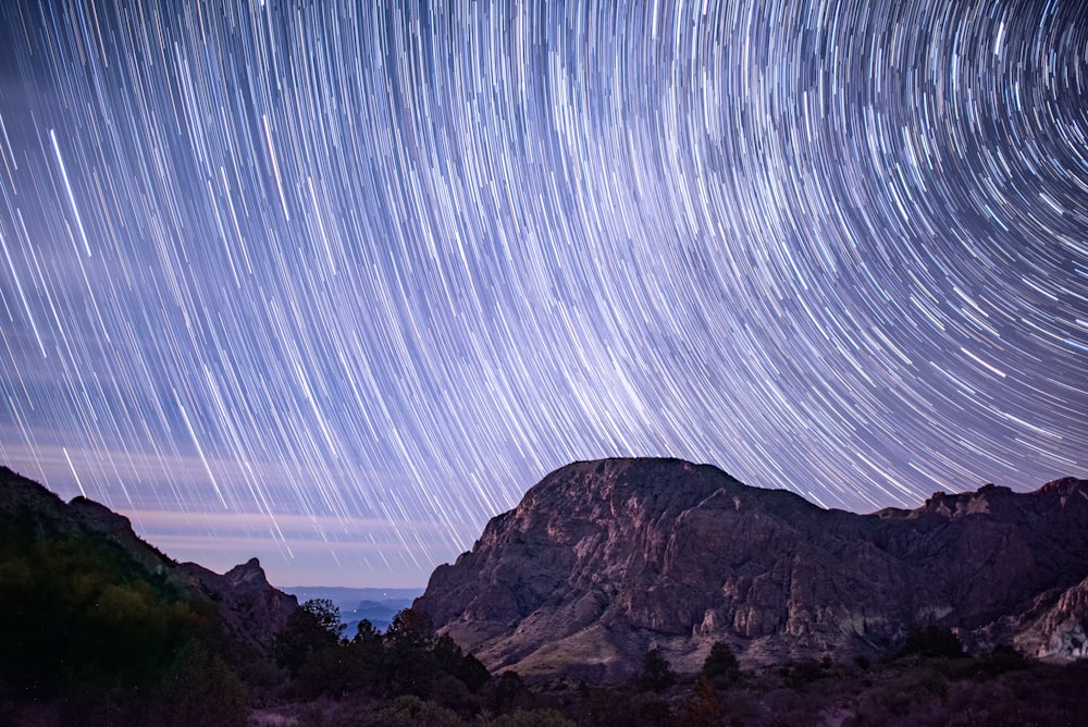 a mountain with a star trail in the sky