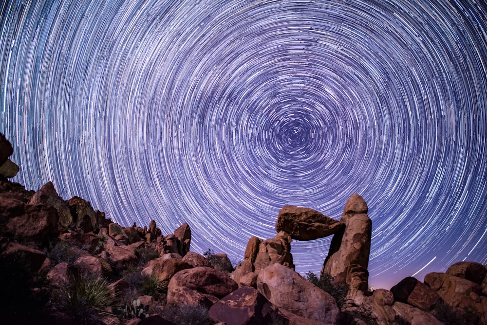 a star trail is shown in the sky above rocks