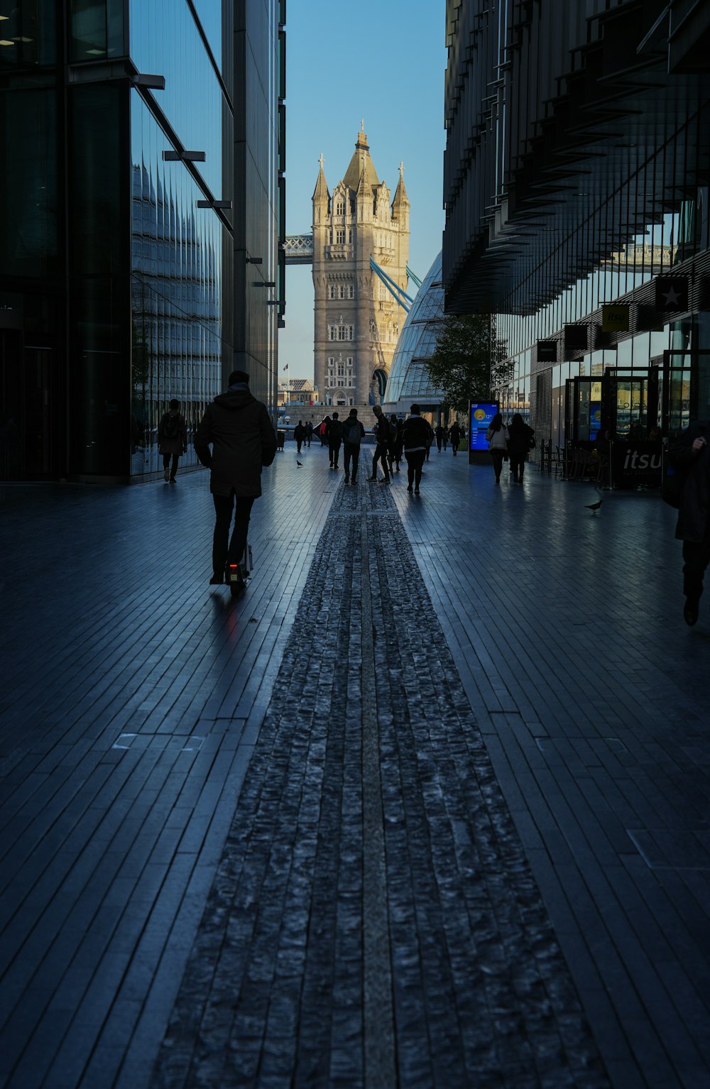 a group of people walking down a street next to tall buildings