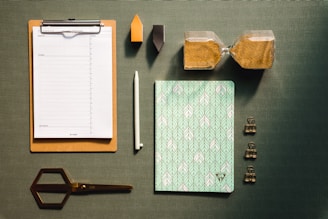 a clipboard with a notepad, pen, paper, scissors and other items