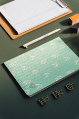 A creative workspace with sketches, mood boards, and a green accent notebook.