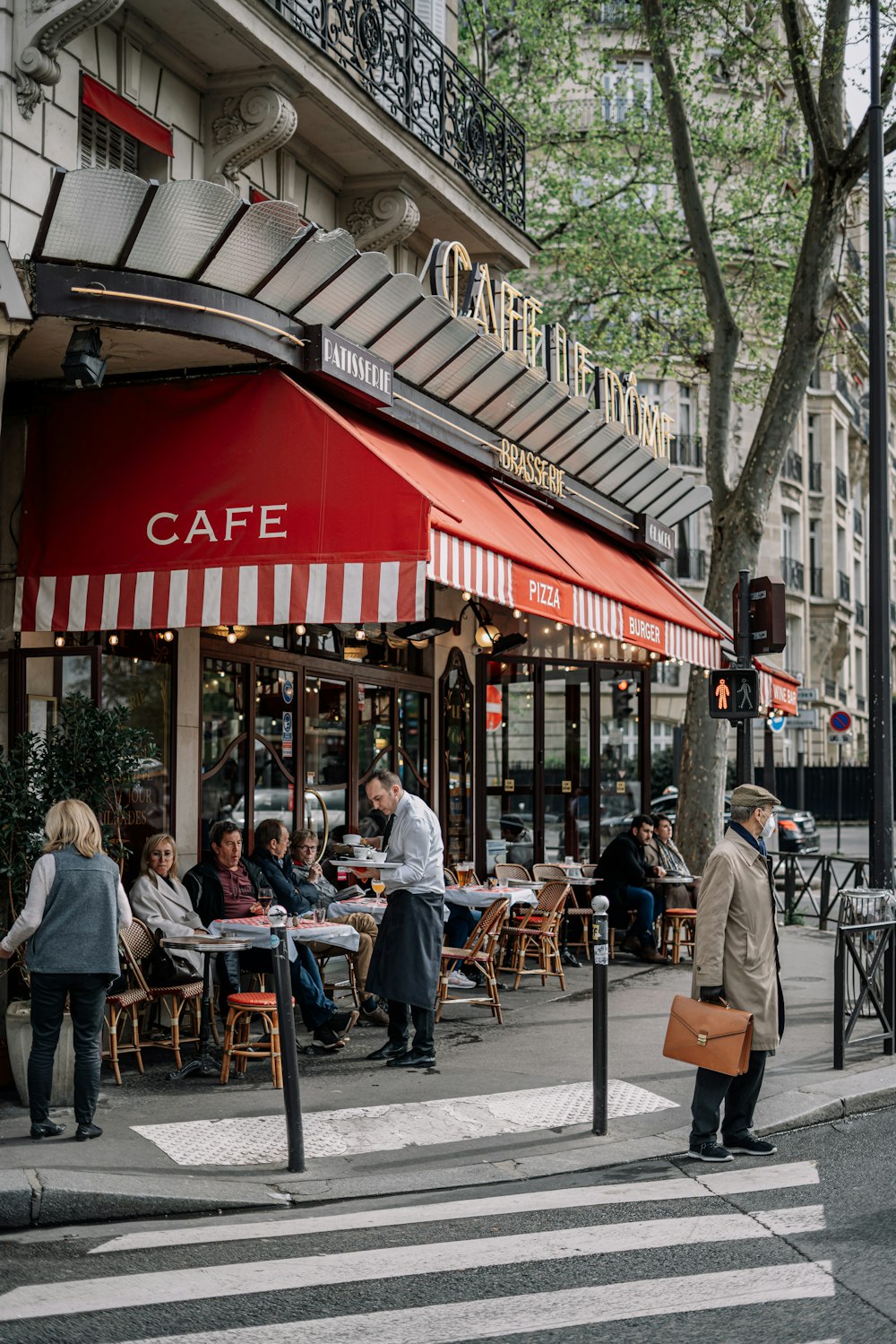 a group of people sitting at tables outside of a cafe