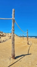 a wooden post on a sandy beach next to the ocean