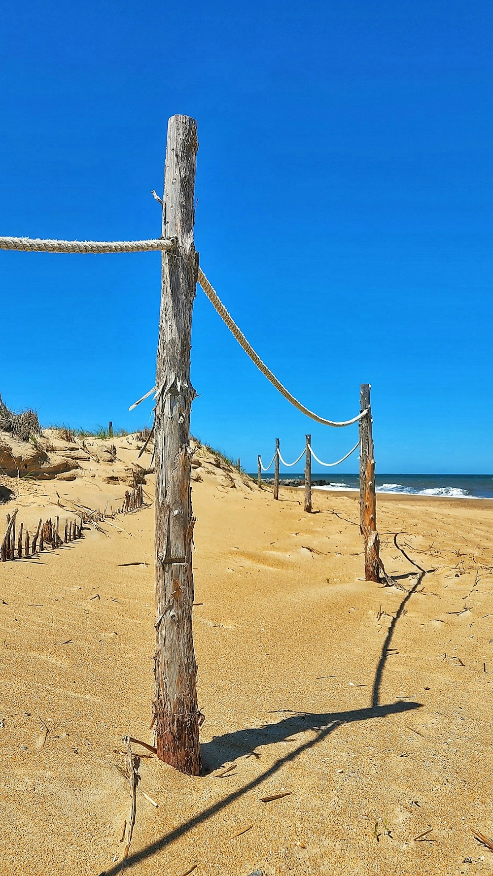 a wooden post on a sandy beach next to the ocean
