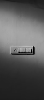 A close-up of a sleek modern wall switch and socket panel installed in a stylish hotel room.