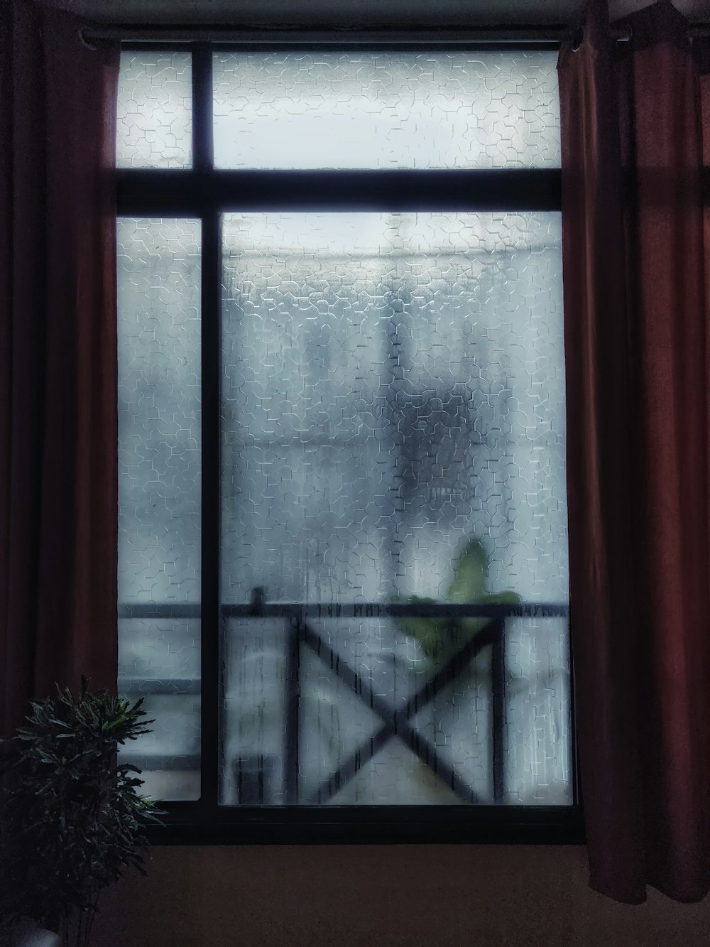 um vaso de planta sentado na frente de uma janela