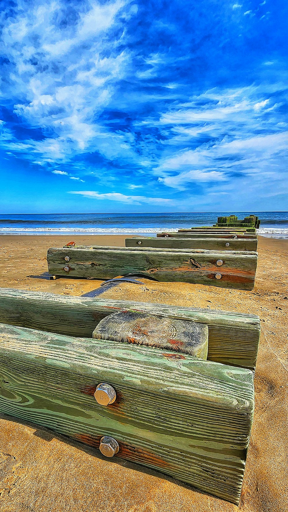 a row of wooden benches sitting on top of a sandy beach