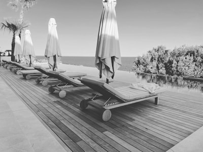 Inviting poolside scene with rustic wooden loungers and the restaurant in the background.