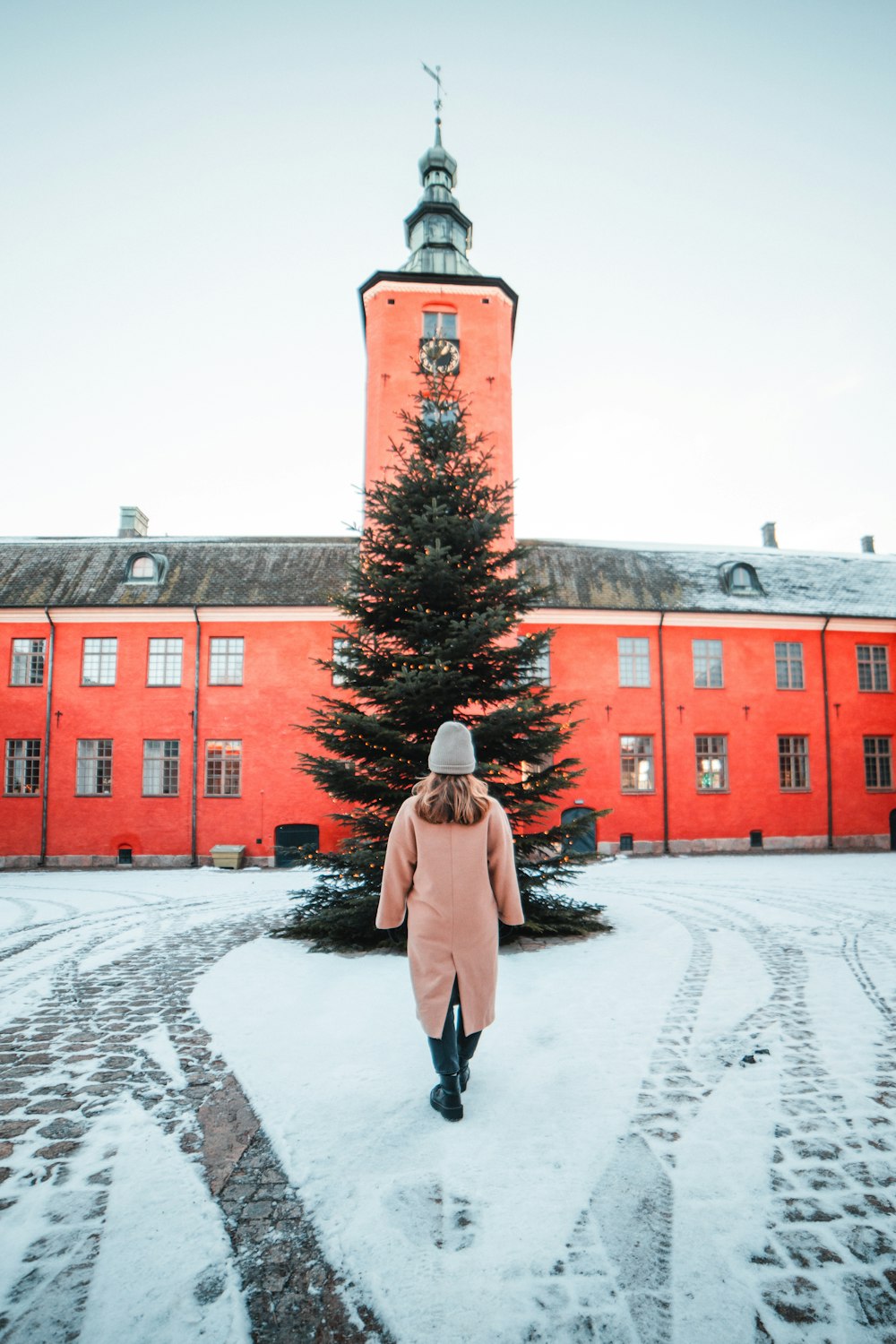 a woman walking in front of a tall red building