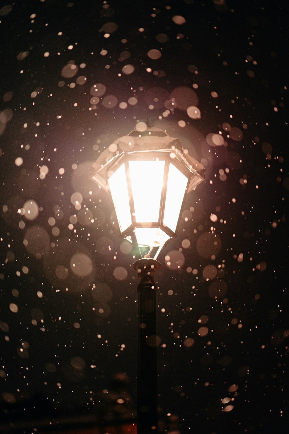 a street light with snow falling on it