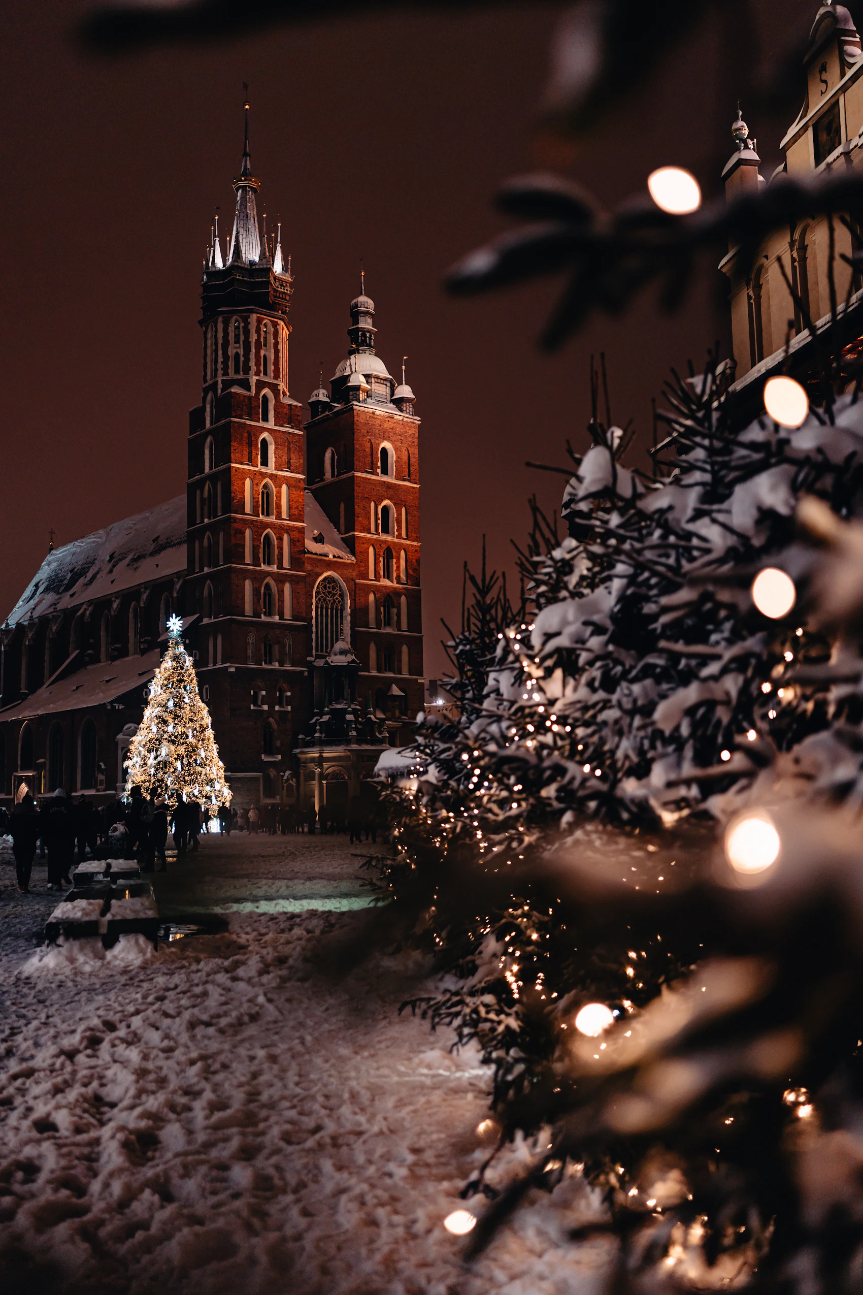 St Mary's Basilica and a Christmas tree in Kraków's Main Square during a snowy winter evening