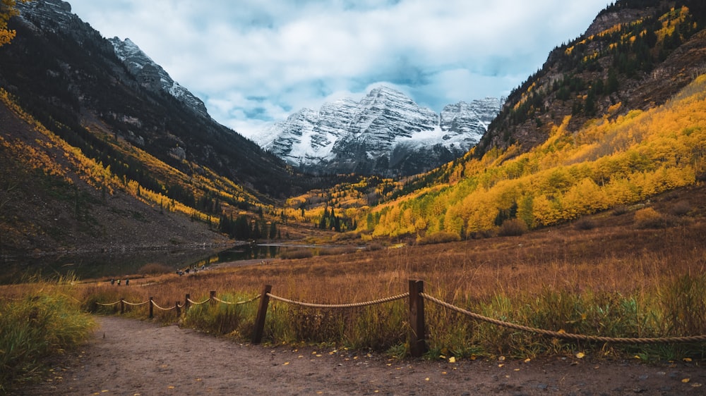 a path leading to a mountain valley with a snow covered mountain in the background