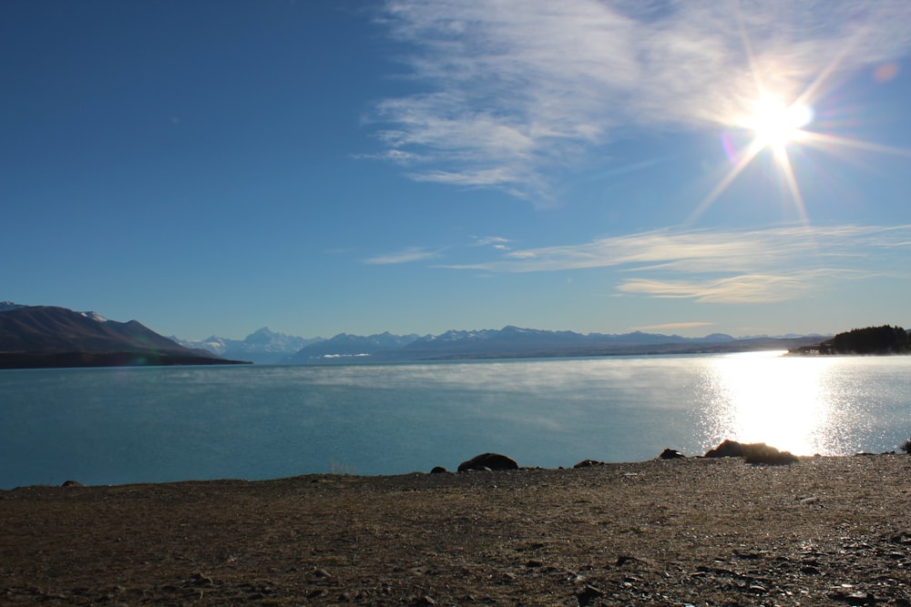 Il sole splende luminoso su un lago con le montagne sullo sfondo