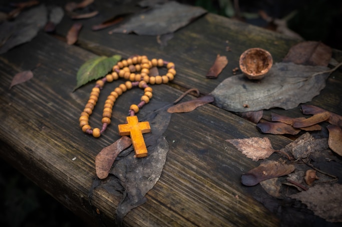 a rosary and a wooden cross on a wooden table