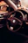 A close-up view of a car interior featuring a Volkswagen steering wheel. The dashboard and part of the driver's side door are visible, with a warm, ambient lighting casting a cozy feel. A golf-themed decorative item is placed on the dashboard.