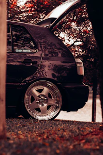 Side view of a shiny used hatchback driving through a leafy suburban street