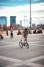 A group of BMX riders performing tricks together at sunset in an urban park.