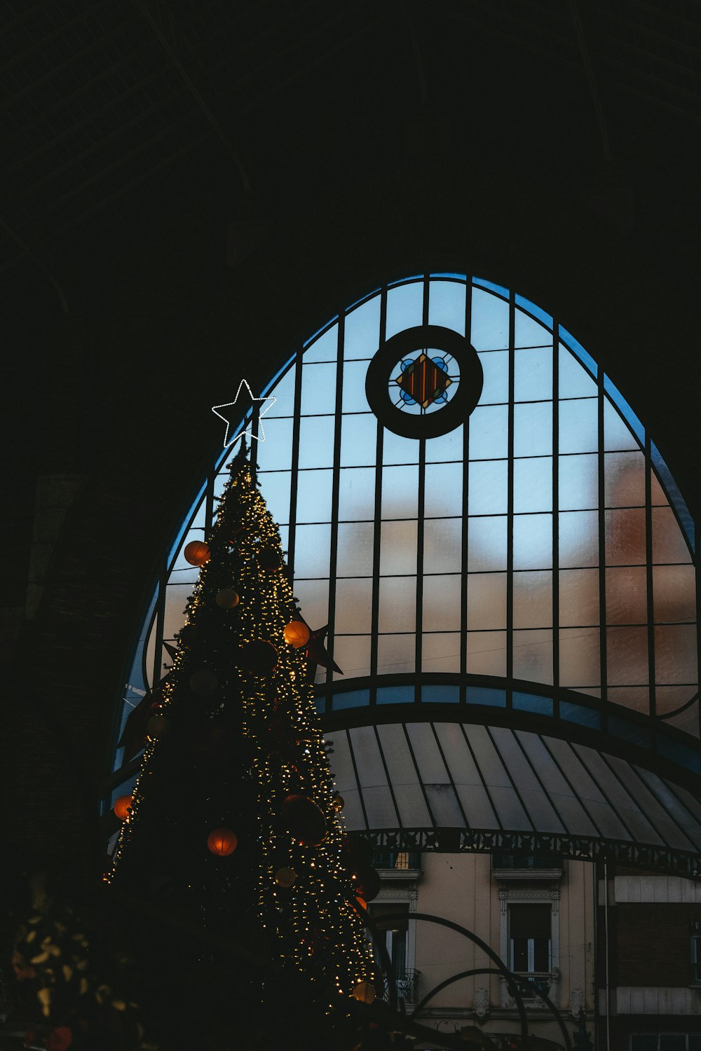 a lit christmas tree in front of a large window