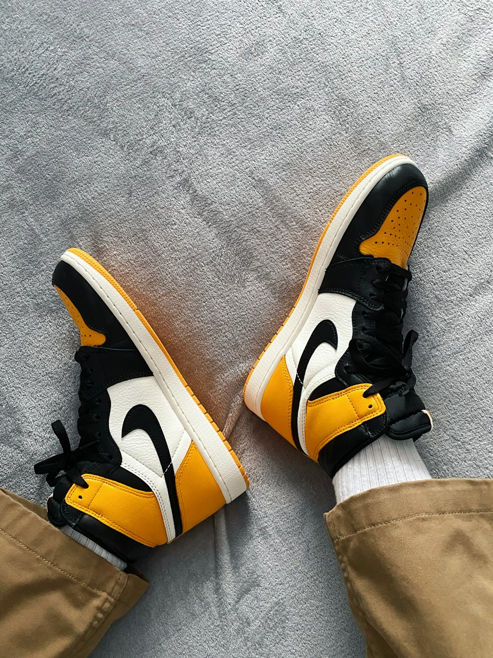a pair of yellow and black sneakers on a bed